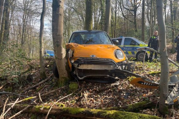 Unfallstelle mit beschädigtem Auto, Polizei und Rettungsdienst, alkoholisierter Fahrer, verletzte Person.