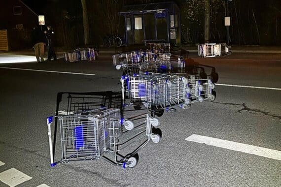 Einkaufswagen liegen verstreut auf der Straße, nach einem Unfall durch ein Fahrzeug.