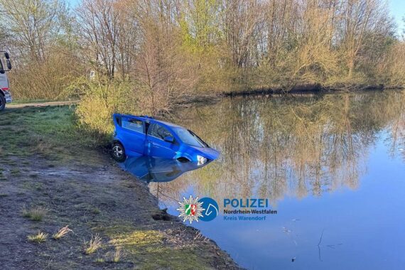 PKW ragt aus einem Teich, Polizei und Abschleppdienst bei nächtlichem Bergungseinsatz.