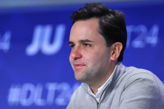 Johannes Winkel auf einem Podium, umgeben von jungen Unionsmitgliedern, bereit für die Wiederwahl.