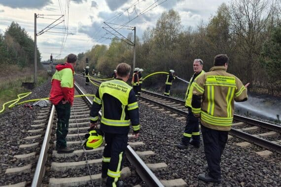 Führungskräfte besprechen Lager bei Einsatz wegen Böschungsbrand; Feuerwehr und Sicherheitskräfte im Fokus.