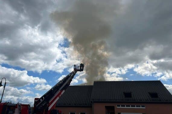Brand in Einfamilienhaus: Dachstuhl in Flammen, Feuerwehr im Einsatz, Bewohner evakuiert.