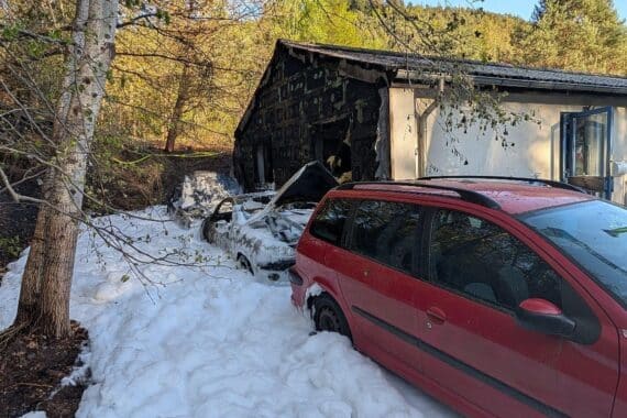 Brände von zwei PKW, Flammen breiten sich auf Wohngebäude aus, Feuerwehr im Einsatz.