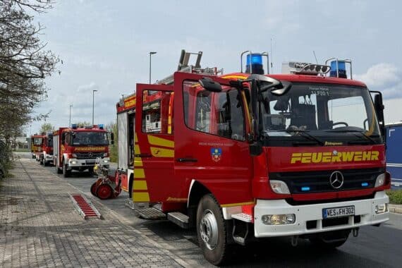 Einsatzfahrzeuge der Feuerwehr vor einem Gebäude, Einsatzkräfte bei Alarmübung oder Fehlalarm.