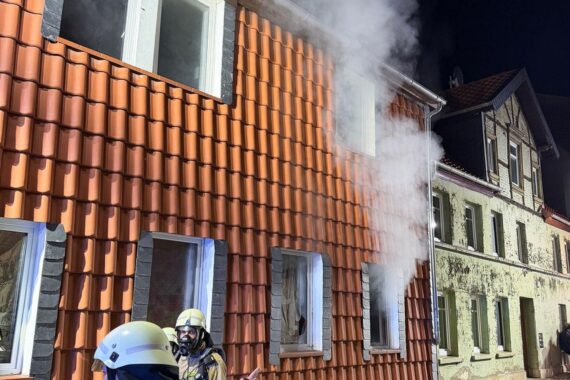 Feuerwehr im Einsatz: Rauchentwicklung bei Zimmerbrand in Mehrfamilienhaus, sichere Evakuierung von Bewohnern.