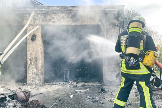 Feuerwehr löscht Garagenbrand, retten Pkw und Gasflaschen, starke Rauchentwicklung sichtbar.