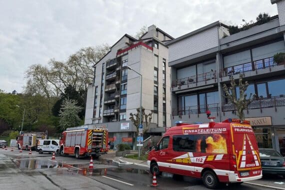 Feuerwehrfahrzeuge sperren Straße, während Einsatzkräfte Wasserschaden durch Rohrbruch beheben.