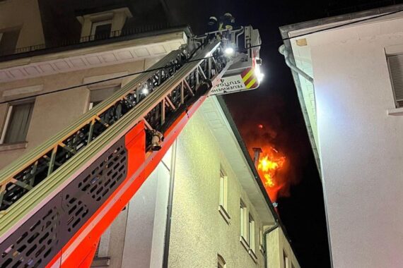 Feuerwehrmann bei Dachstuhlbrand in Stuttgart-Zuffenhausen, Flammen und Rauch sichtbare Gefahr.