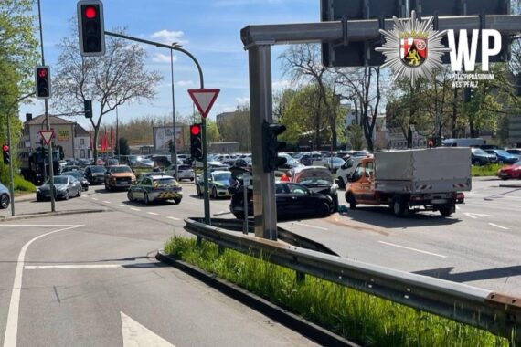 Zwei beschädigte Autos an einer Kreuzung, Einsatzfahrzeuge der Polizei, möglicherweise Zeugen gesucht.