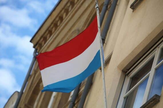 Luxemburgische Fahne vor einem Hintergrund, der die Deutsch-Luxemburgische Grenze symbolisiert.