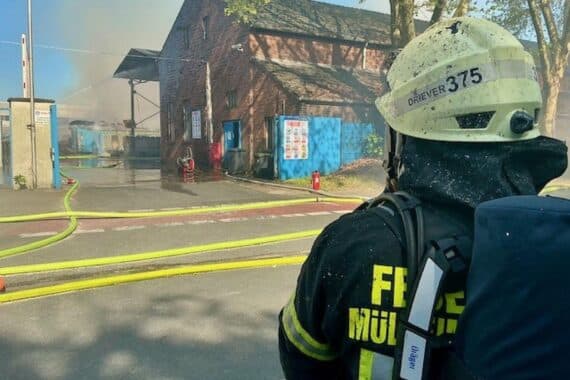 Großbrand in Gewerbebetrieb, Feuerwehr im Einsatz, Rauchsäule, gebranntes Altpapier, verletzte Person.