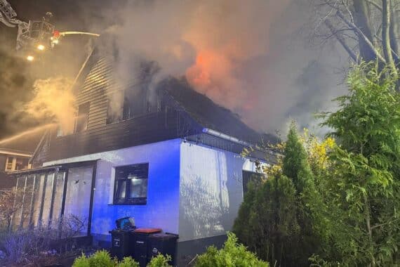 Zwei beschädigte Einfamilienhäuser, Feuerwehr im Einsatz, hohe Flammen und Rauch sichtbar.