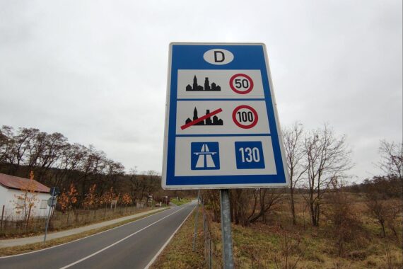 Tempolimit-Schild auf Autobahn, Fahrer im Auto, Diskussion über Geschwindigkeitsbegrenzungen in Deutschland.