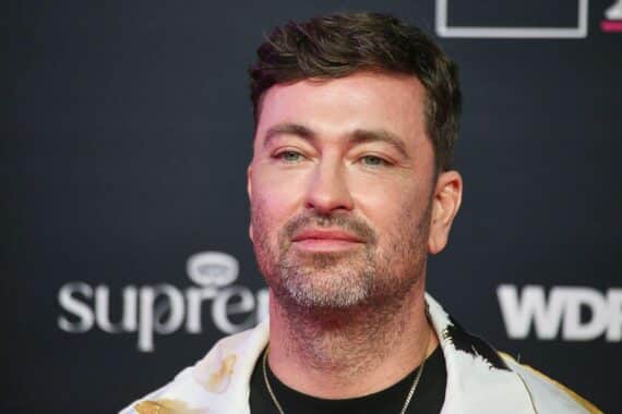 Marteria feiert Nummer-eins-Album, umgeben von Charts und anderen erfolgreichen Künstlern.
