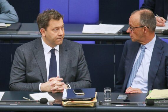 Friedrich Merz diskutiert Steuerreform; Lars Klingbeil im Hintergrund, beide in politischem Austausch.