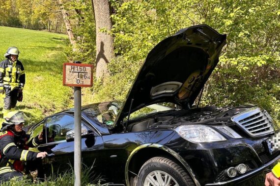 Feuerwehr bei Fahrzeugbergung aus Straßengraben, Person in Auto, Unfallursache unklar.