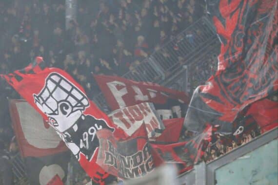 Nürnberger Fans marschieren jubelnd zum Stadion, während Polizei für Sicherheit sorgt.