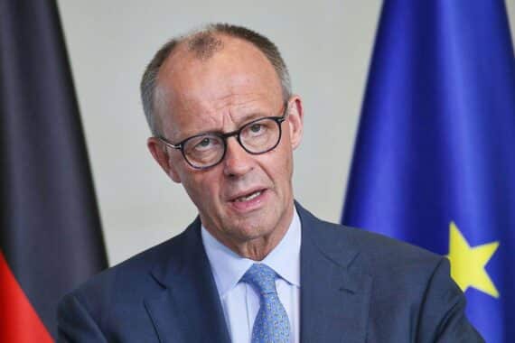 Friedrich Merz spricht beim politischen Treffen, umringt von Parteikollegen und Journalisten.