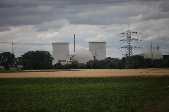 Ein Atomkraftwerk im Hintergrund, umgeben von Windkraftanlagen und Sonnenkollektoren.