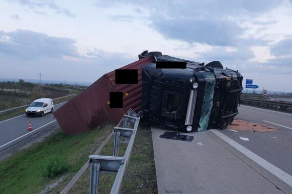 Sattelzug liegt auf der Seite, durchbrochene Schutzleitplanke, Unfallstelle, Einsatzkräfte, gesperrte Autobahn.