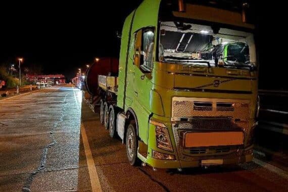 Überladener Schwertransporter mit Kabeltrommel und Stahlseil auf der Autobahn rastet.