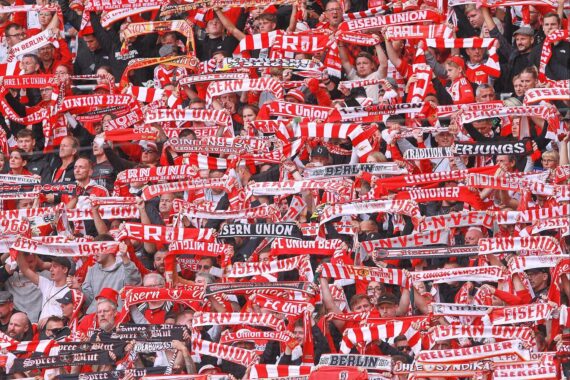 Marie-Louise Eta, erste Trainerin der Bundesliga, umgeben von Union Berlin-Fans in Begeisterung.