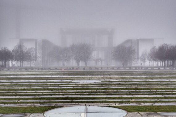 Bundeskanzleramt im Nebel, während die Sonne hinter Wolken aufgeht. Ein wechselhaftes Wetterzeichen.