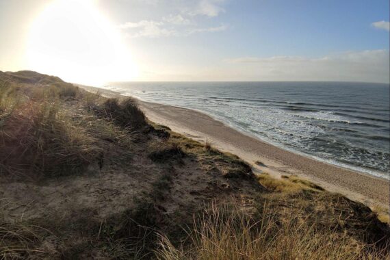 Sonniger Strand mit Dünen, symbolisiert ruhiges Hochdruckwetter in Schleswig-Holstein und Hamburg.