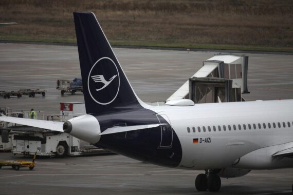 Lufthansa-Maschine im Hintergrund, streikende Piloten und Passagiere am Flughafen im Vordergrund.