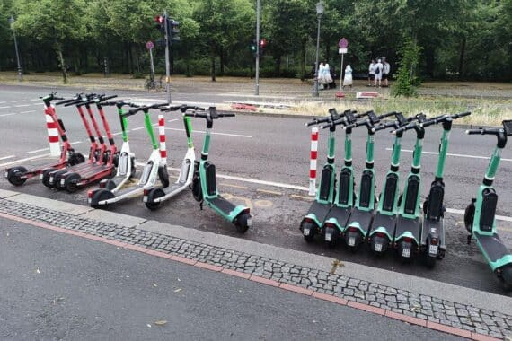 E-Scooter am Unfallort, umgeben von Absperrungen und Polizei, nach tragischem Vorfall.