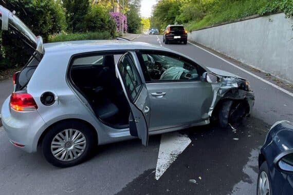Ein beschädigtes Auto, das gegen eine Mauer prallte; Polizei und Rettungsdienst vor Ort.