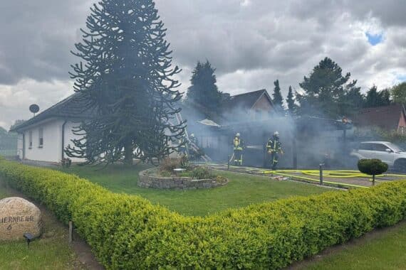 Löscharbeiten an brennendem Auto, Feuerwehr im Einsatz, verletzte Personen, Rauch und Flammen sichtbar.