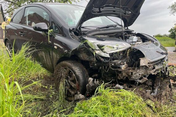 Unfallstelle mit verunfalltem Auto im Graben, Rettungswagen und Polizei im Einsatz.