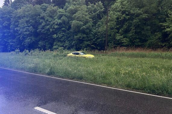 Ein Hyundai steht im Grünstreifen, umgeben von nasser Fahrbahn und Vegetation.