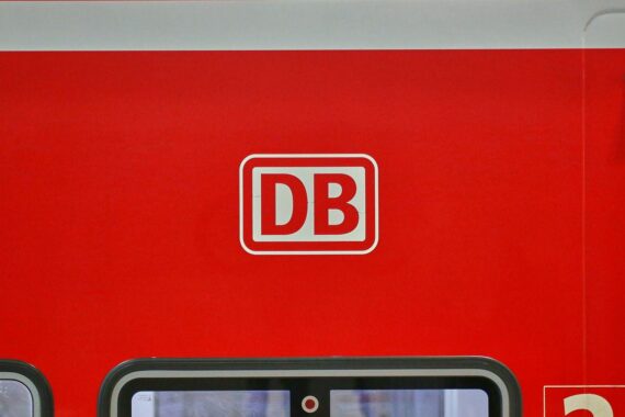 Logo der Deutschen Bahn vor Baustelle, Gleise und Weichen, mit Hinweisen auf Fahrgäste.