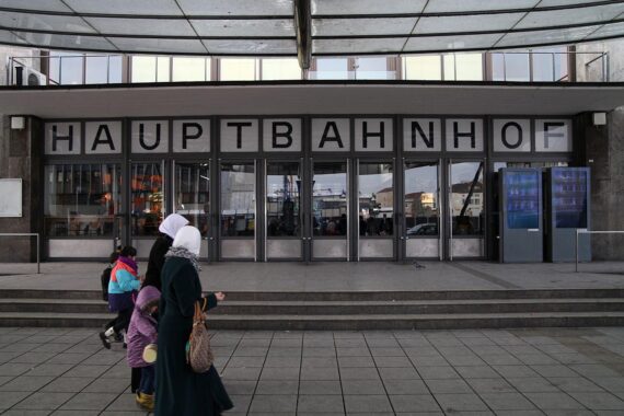 Frauen mit Kopftuch vor dem Ulmer Hauptbahnhof, symbolisch für kulturelle Vielfalt und Mobilität.