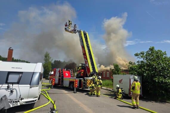 Feuerwehr löscht Dachstuhlbrand, Einsatzkräfte mit Löschtechnik und Drohne im Einsatz.