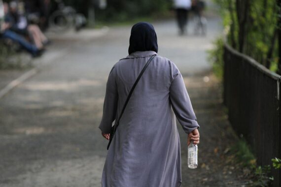 Frau mit Kopftuch, Symbol für muslimische Identität und Gemeinschaft, umgeben von Sorgenfalten.