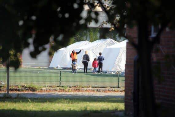 Flüchtlingsfamilie in Zeltstadt, symbolisiert Integration und neue Chancen in Deutschland.