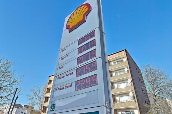 Tankstelle mit Preisanzeige, Autofahrer, Diskussion über Tankrabatt und steigende Energiepreise.
