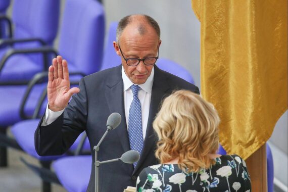 Friedrich Merz vor dem Bundestag, umgeben von Symbolen politischer Unzufriedenheit und Kritik.