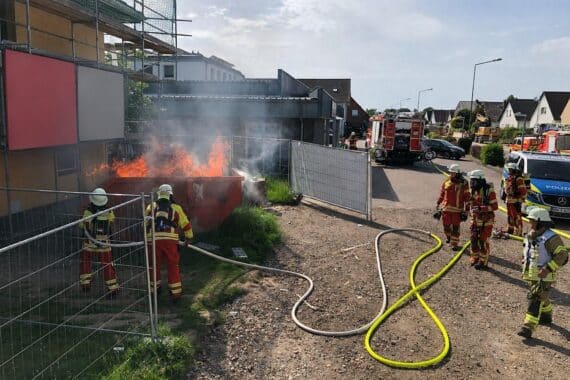 Brennende Mulde auf Baustelle, Feuerwehr im Einsatz, Unwetterfolgen bekämpfen.