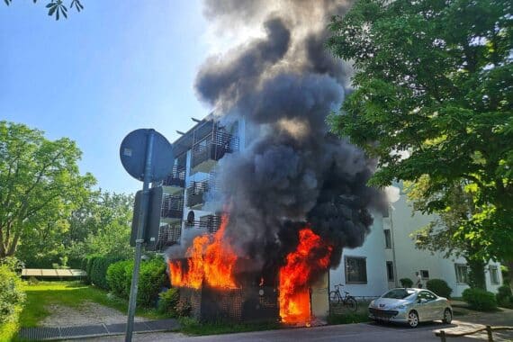 Feuerwehr löscht Brand an Gebäude; starker Rauch, Einsatzkräfte mit Atemschutz, Kontrolle der Wohnungen.