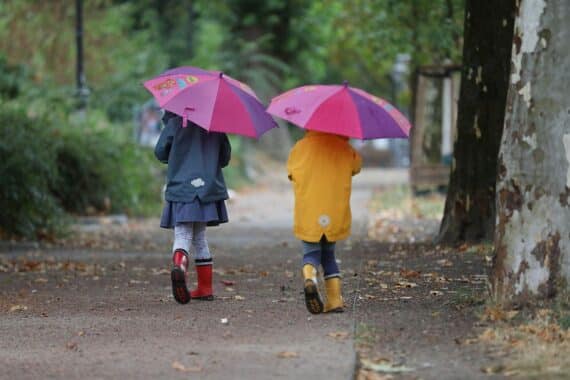 Zwei Kleinkinder spielen im Herbst, während Gewitter und Starkregen in der Umgebung drohen.