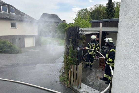 Feuerwehr gelöscht Heckenbrand, Kontrolle mit Wärmebildkamera, Einsatzkräfte und Polizei vor Ort.