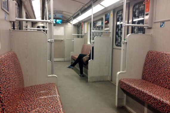 Einsam sitzende Frau in leerer U-Bahn, symbolisiert Isolation und Bedrohung in urbaner Umgebung.