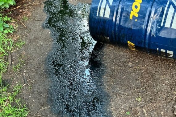 Illegal entsorgte Ölfässer auf Waldweg, Gefahr für Umwelt und polizeiliche Ermittlungen.