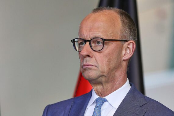 Friedrich Merz steht enttäuscht, umgeben von unzufriedenen Bürgern und kritischen Medien.