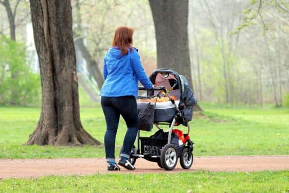 Mutter mit Kindern im Vordergrund, symbolisiert Herausforderungen junger Familien und den Elterngeld-Diskurs.