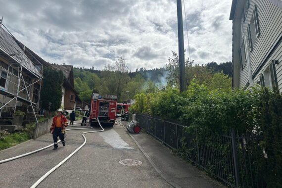 Küchenbrand im Dachgeschoss, Feuerwehrlöscharbeiten, Einsatzkräfte, rauchige Atmosphäre, beschädigtes Gebäude.
